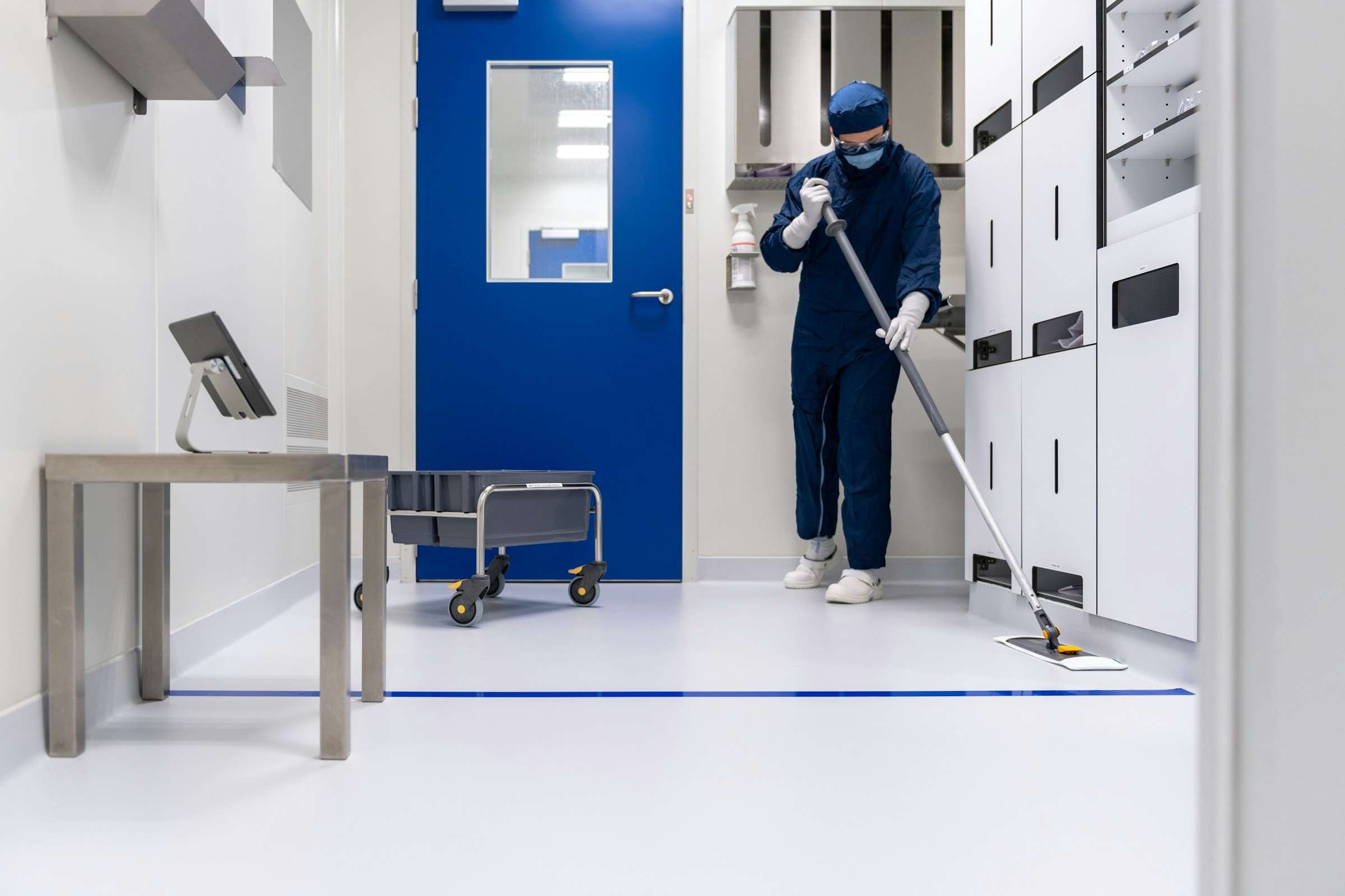 Profesional de limpieza pasando la mopa por el pasillo de una instalación