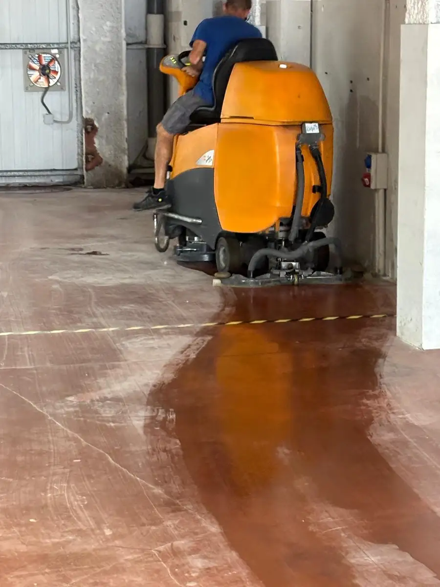Operario conduciendo una fregadora industrial durante la limpieza de un suelo