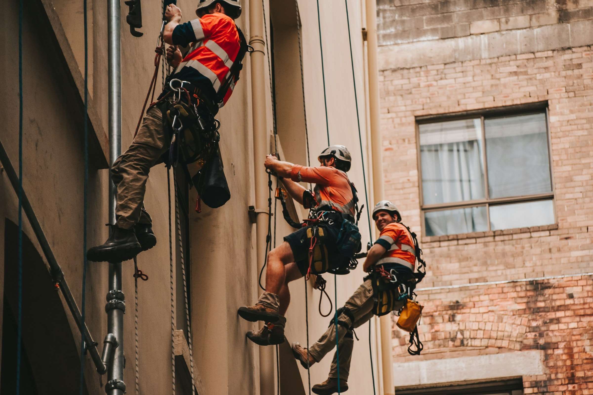 Tres técnicos de trabajos verticales suspendidos en la fachada de un edificio